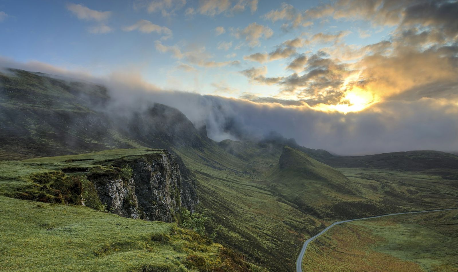 Clouds rolling over a green ridge